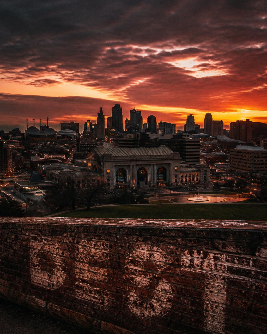 Kansas City skyline at dusk over a brick wall